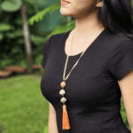 Collar largo con 3 esferas de arcilla polimérica en colores sutiles, con incrustaciones de pewter y cristal y terminado en cinta metálica dorada.