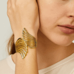 Expresivo brazalete de aleación de metales dorada, con diseño de alas conectando cielo y tierra